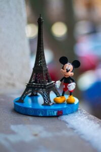 mickey mouse figurine beside eiffel tower miniature