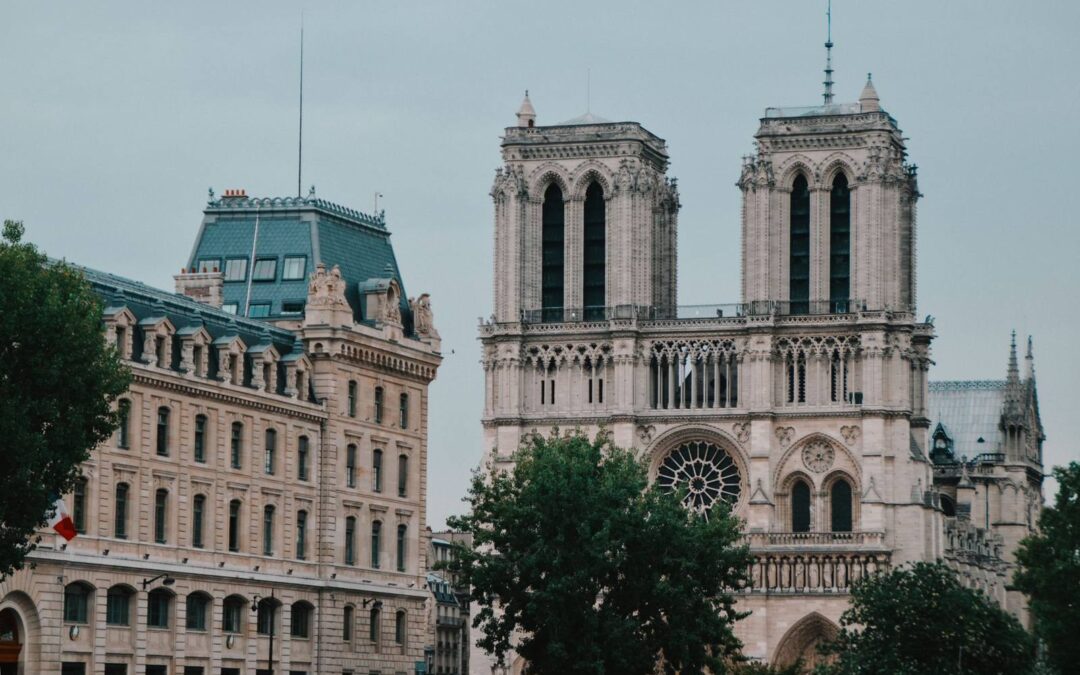 View of the iconic Notre-Dame Cathedral in Paris, France against a cloudy sky.