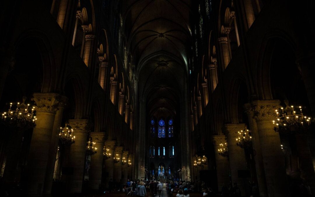 Dimly lit gothic cathedral interior showcasing beautiful arches and columns with stained glass windows.